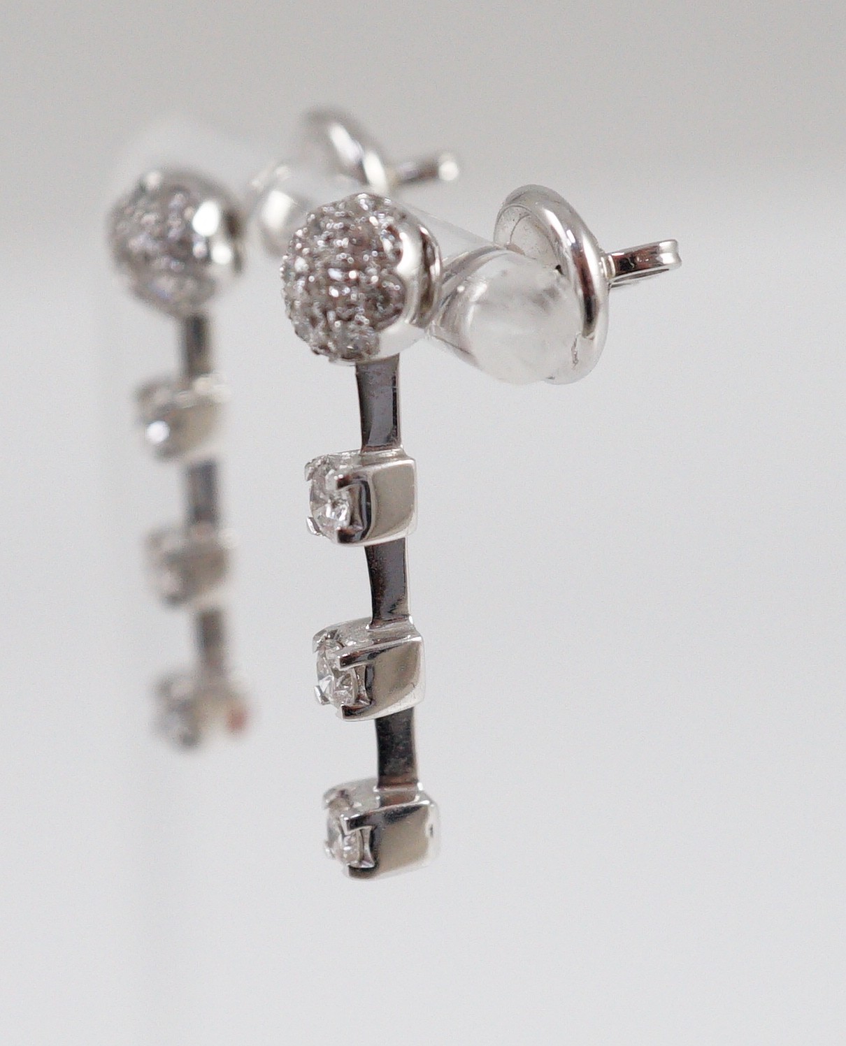 A modern pair of 18ct white gold, diamond cluster and three stone diamond drop set earrings